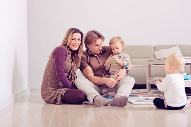 Happy family sitting on floor with their little babies Family spending time at home with their son and daughter. - Foto, immagini