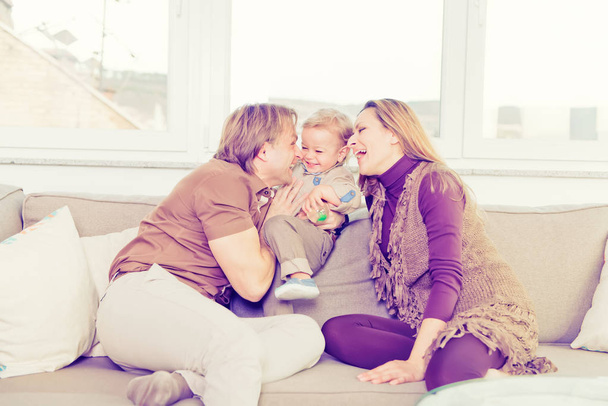 Portrait of happy family sitting on the sofa and playing. - Fotoğraf, Görsel
