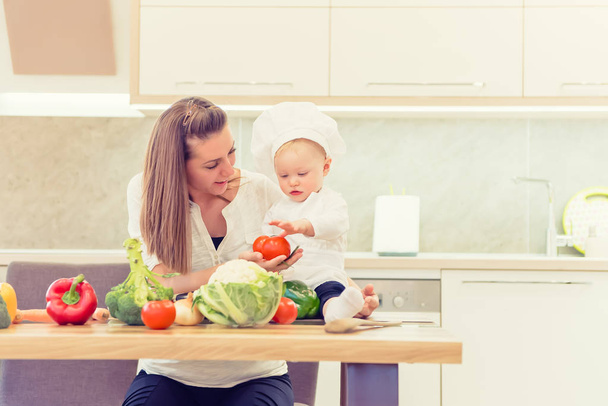Happy parents sitting in the kitchen and prepares for cooking with their baby girl chef. - 写真・画像