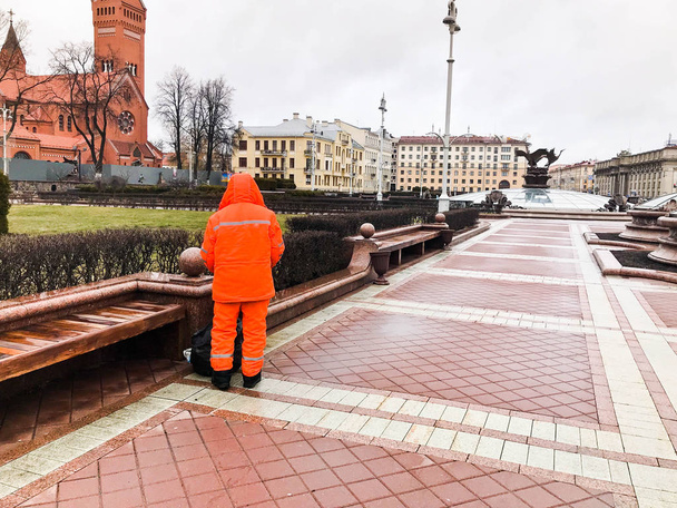 Male working cleaner in orange overalls wearing robe clothes working cleans the streets of the city - Fotoğraf, Görsel