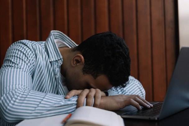 Müder und frustrierter Mann, der am Laptop schläft, er arbeitet hart, Burnout und Stress am Arbeitsplatz. Arbeitszeitkonzept. Freiberufler versäumte Frist, fühlte sich erschöpft. - Foto, Bild