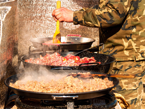Onherkenbaar persoon koken traditionele food chichas opgeroepen de straat op een populaire feestje in een dorp in Spanje - Foto, afbeelding