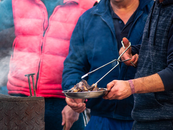Onherkenbaar persoon koken varkensvlees op een barbecue in de straat op een populaire feestje in een dorp in Spanje - Foto, afbeelding
