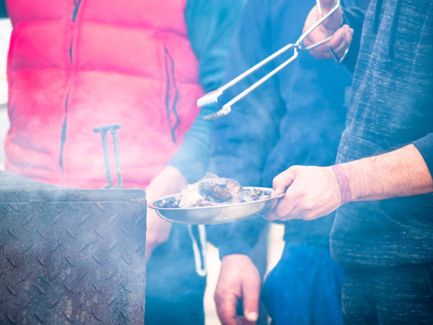 Onherkenbaar persoon koken varkensvlees op een barbecue in de straat op een populaire feestje in een dorp in Spanje - Foto, afbeelding