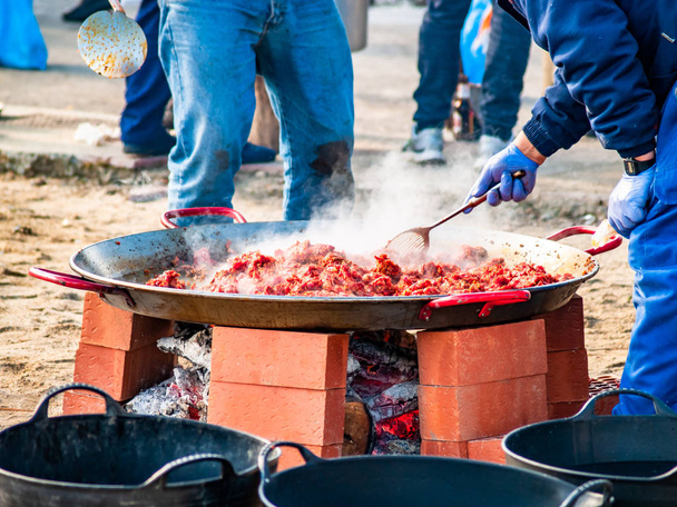 Nie do poznania osoby gotowania tradycyjnych potraw o nazwie chichas na ulicy popularnej imprezie w wiosce w Hiszpanii - Zdjęcie, obraz