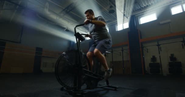 Hombre joven con sobrepeso haciendo ejercicio con una bicicleta estática
 - Imágenes, Vídeo