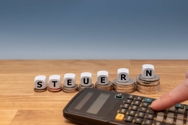 サイコロのフォーム"Steuern"(英語では「税」) のドイツ語の単語の上に - 写真・画像