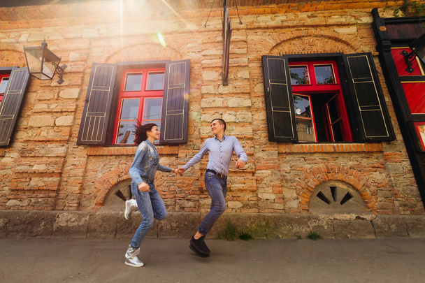 couple running fast neat brick building with red windows - Zdjęcie, obraz