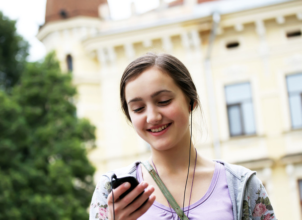 Menina ouvindo música no telefone celular na cidade
 - Foto, Imagem