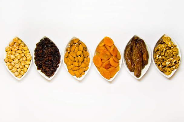 Assortment of nuts and dried fruits in bowls on a white background top view with copyspace - Fotoğraf, Görsel