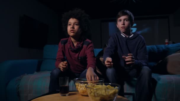 Scared teens eating popcorn during horror movie - Кадри, відео