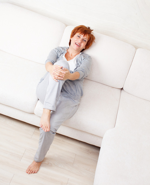 Gelukkig volwassen vrouw op sofa - Foto, afbeelding