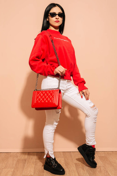 Beyaz kot pantolon ve kazak kırmızı çanta debriyaj elinde genç kadın moda - Fotoğraf, Görsel