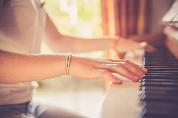 Girl is playing piano at home, high angle view, blurry backgroun - Foto, Imagem