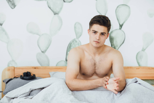 young handsome man on bed in room waking up  - Foto, afbeelding