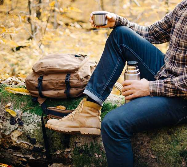 Man resting on fallen tree trunk with thermos. - Foto, Imagem