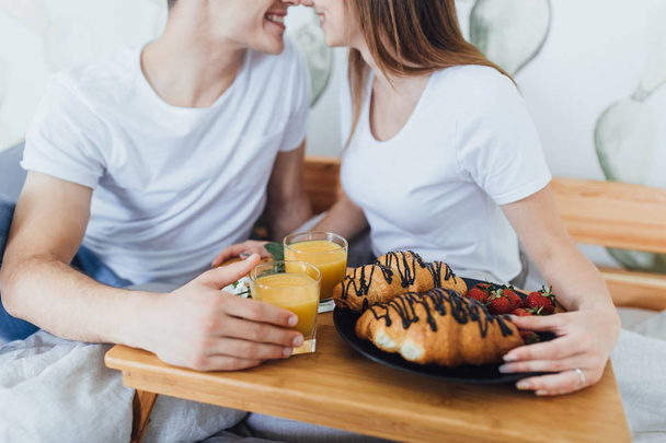 Young beautiful couple having breakfast in morning on bed, selective focus - Фото, зображення