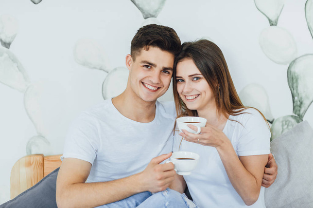 Young cute couple drinking coffee in bed at home, selective focus - Foto, afbeelding