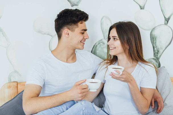 Young cute couple drinking coffee in bed at home, selective focus - Valokuva, kuva