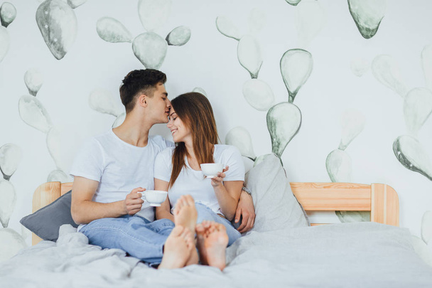 Young cute couple drinking coffee in bed at home, selective focus - Foto, imagen