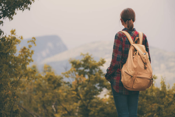 Jeune fille hipster avec sac à dos profitant du coucher de soleil sur le sommet de la montagne brumeuse
. - Photo, image