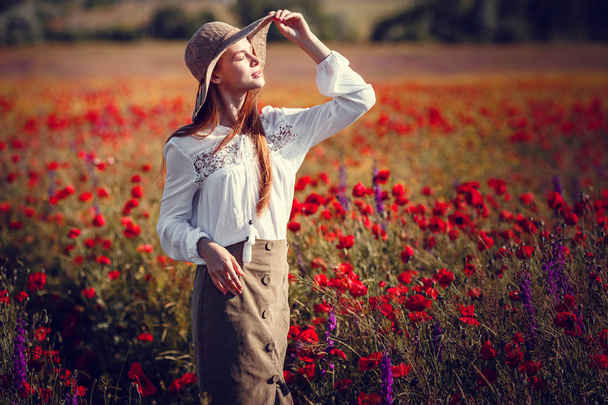 Young beautiful woman walking and dancing through a poppy field - Foto, Imagem