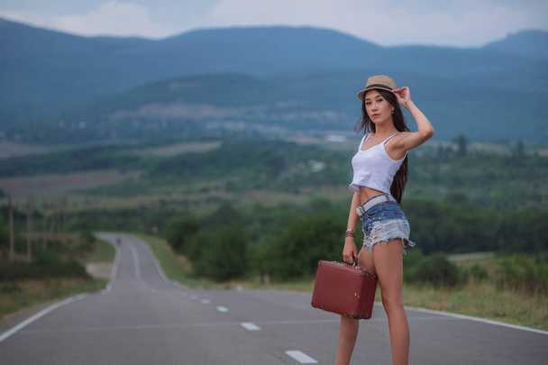 women is hailing a car on a road. Thumbing a ride. Outdoors vacation.. - Photo, Image