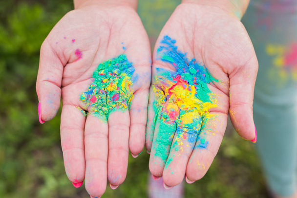 Holiday, festival holi and family concept - Palms of young people covered in different colors over nature background - Fotografie, Obrázek
