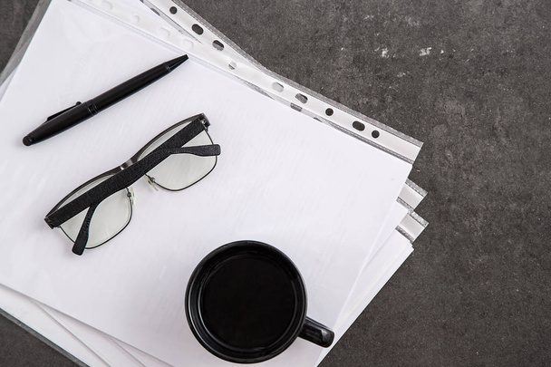 Taza negra de café y bolígrafo negro sobre documentos sobre fondo de mármol gris. Vista superior
 - Foto, Imagen