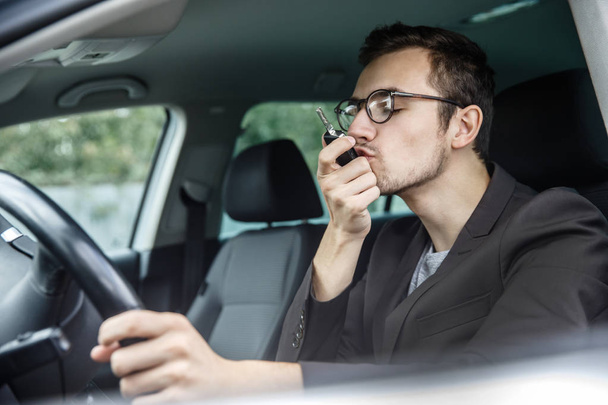 Tyytyväinen nuori mies suutelee autonavaimiaan istuessaan autossa. Hänen vasen kätensä on ratissa.
. - Valokuva, kuva