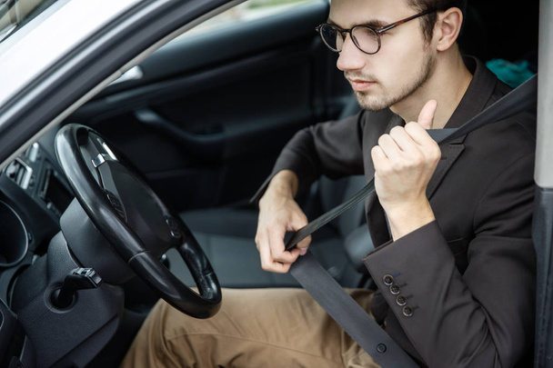 Young man clips on his belt. He is sitting at his car. Road safety concept. - Fotografie, Obrázek