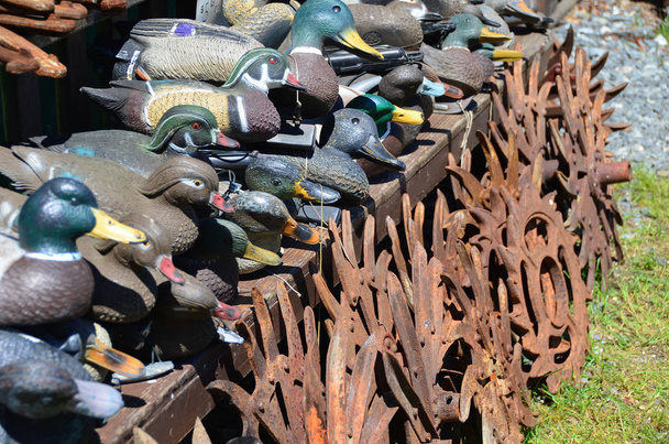 ein Haufen antike Entenköder vor antiken metallenen landwirtschaftlichen Geräten auf einem Freiluftmarkt - Foto, Bild