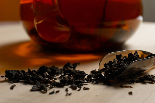 Gros plan feuilles de thé noir sur la table avec cuillère à thé
 - Photo, image