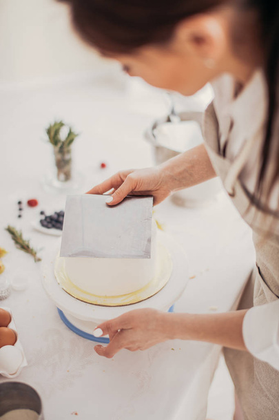 womans hand holding a pstry cutter while preparing cake - Foto, Bild