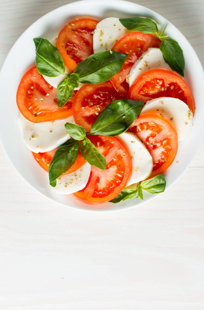 Close-up foto van caprese salade met rijpe tomaten, basilicum, buffalo mozzarella kaas. Italiaanse en mediterrane voedsel concept. Frisse en gezonde biologische maaltijd. Starter en antipasti.  - Foto, afbeelding
