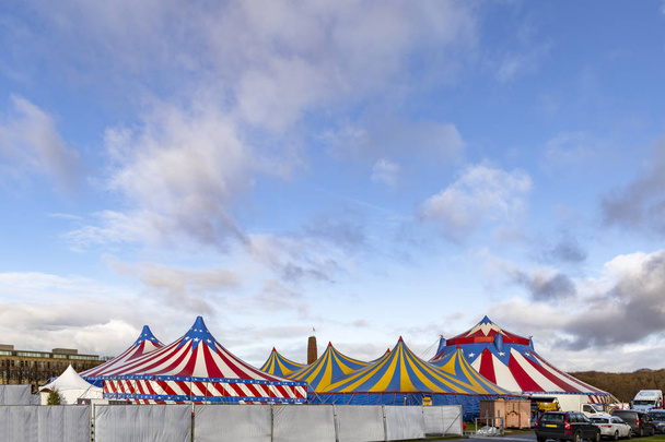 Red and white circus tents topped with bleu starred cover against a sunny blue sky with clouds - Photo, Image