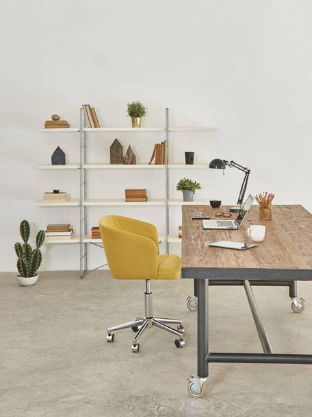 Сучасний стілець та офісний стіл, книжкова шафа з настільною лампою та ноутбуком
 - Фото, зображення