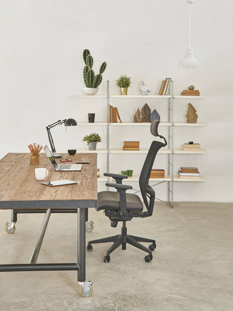 Μοντέρνα καρέκλα γραφείου και τραπέζι, βιβλιοθήκη με λάμπα tablet και laptop - Φωτογραφία, εικόνα