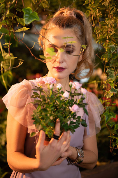 Nice young woman looking at beautiful roses - Foto, Bild