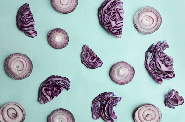 Bright pattern made with onion rings and chopped red cabbage on blue surface - Photo, Image