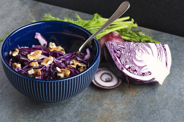 Delicious vegetarian dinner or snack with red cabbage,dill,onion rings,nuts.Served on rustic grey dark table - Photo, Image