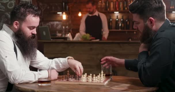 Twee stijlvolle hipsters met baarden die een vriendschappelijk schaakspel spelen - Video