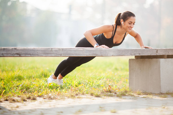 Фитнес. Концепция спорта, отдыха и мотивации. Атлетичная женщина, стоящая на доске на улице на закате
 - Фото, изображение