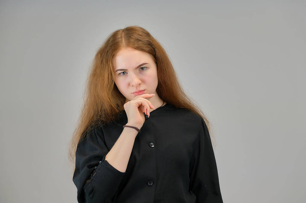Concept retrato de uma linda menina adolescente com cabelo vermelho em um fundo cinza sorrindo e falando
. - Foto, Imagem