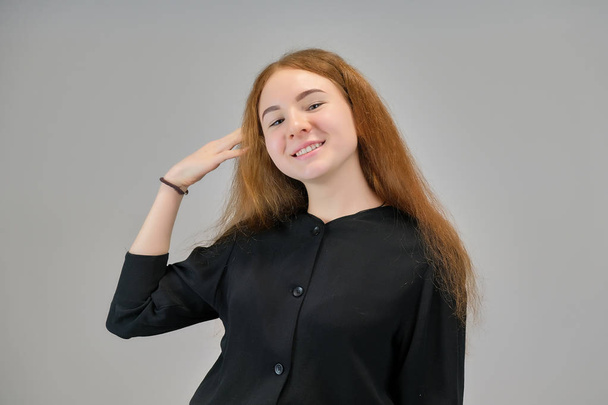 Concept portrait of a cute pretty teenager girl with red hair on a gray background smiling and talking. - Fotografie, Obrázek