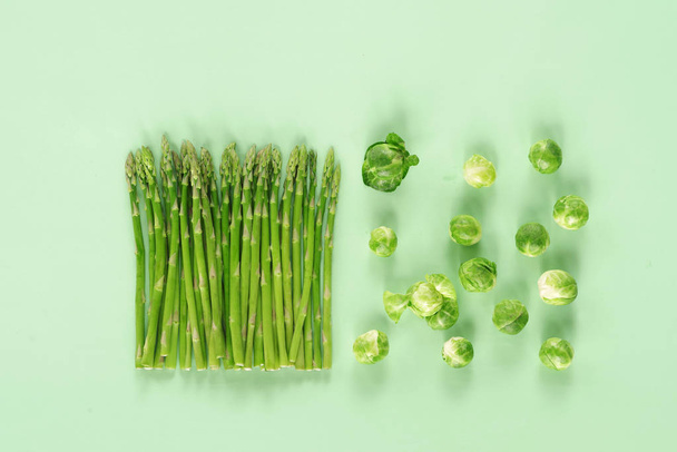 Asparagus and Brussels sprouts on a light green background. Top view. - Photo, Image