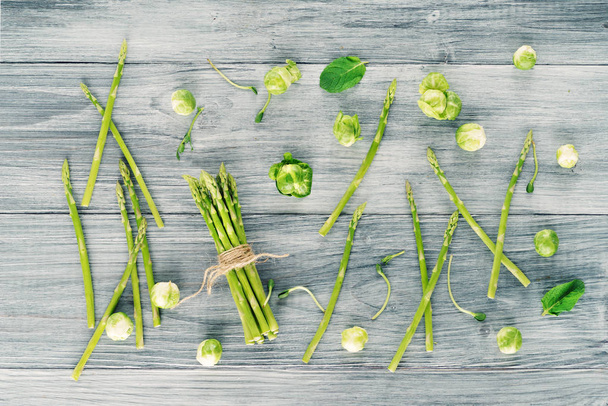 Espargos e verduras verdes de primavera em um fundo de madeira
. - Foto, Imagem