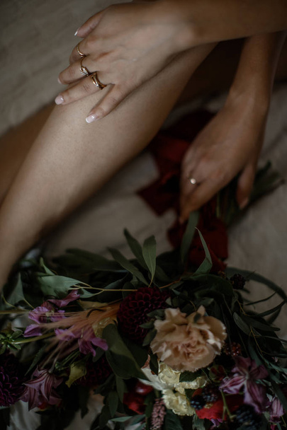 Female hand holding big flower bouquet closeup. Her another hand is laying on her crossed legs. - Φωτογραφία, εικόνα