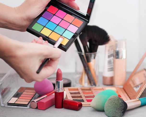 Pinceaux cosmétiques professionnels, ombres, rouges à lèvres et éponges sur une table grise
  - Photo, image