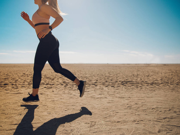 vista ritagliata di allenamento jogger sulla spiaggia di sabbia
  - Foto, immagini
